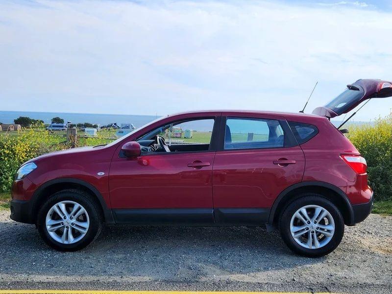 A red Qashqai Acenta viewed from the passenger side