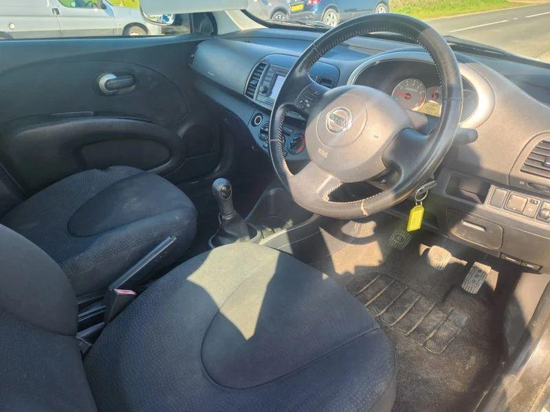 The steering controls of a black Nissan Micra viewed from above the driver seat