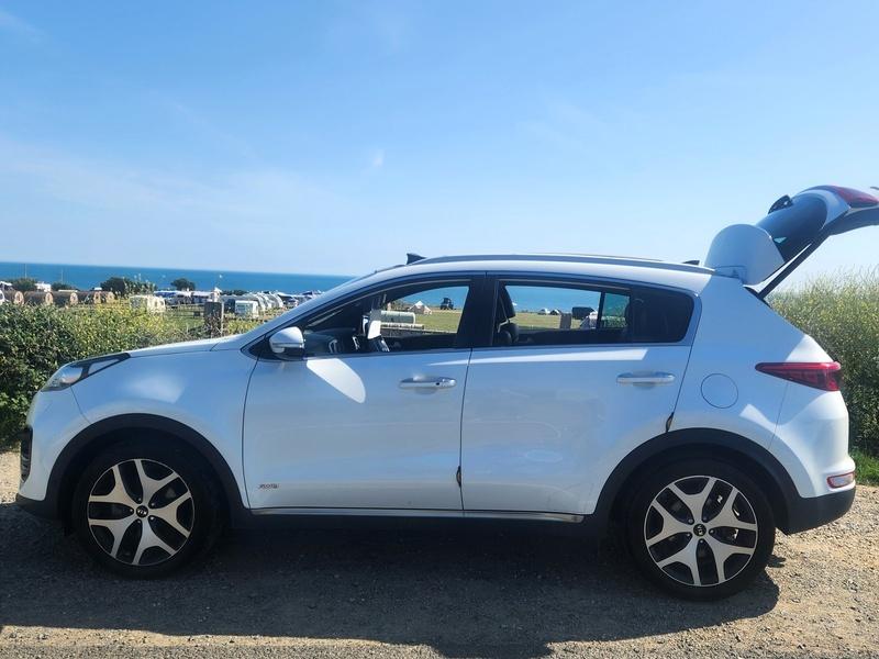 A white KIA Sportage viewed from the passenger side