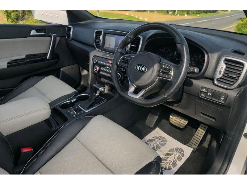 The steering controls of a white KIA Sportage viewed from above the driver seat