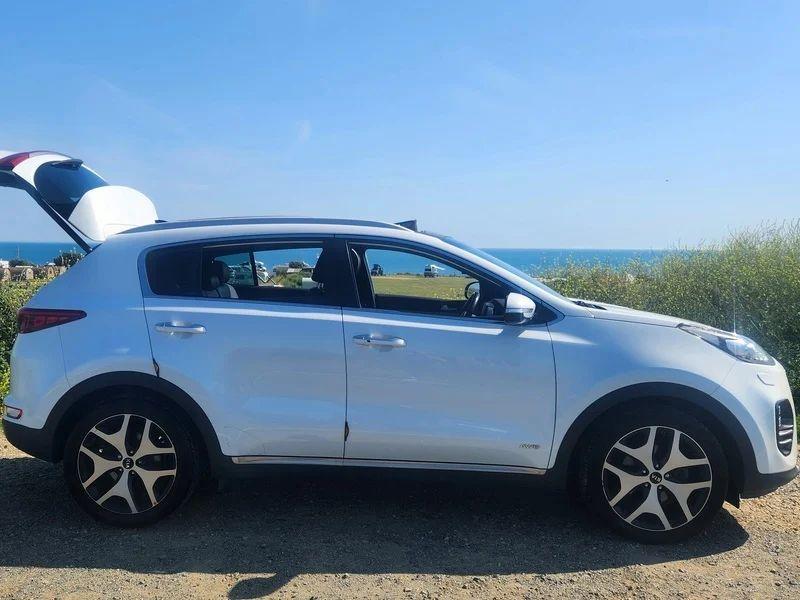 A white KIA Sportage viewed from the driver side