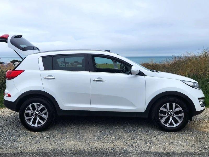 A white Kia Sportage viewed from the driver side