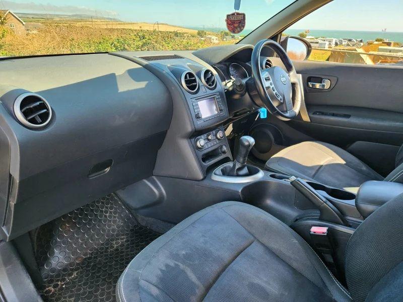The steering controls of a gold Nissan Qashqai viewed from above the passenger seat