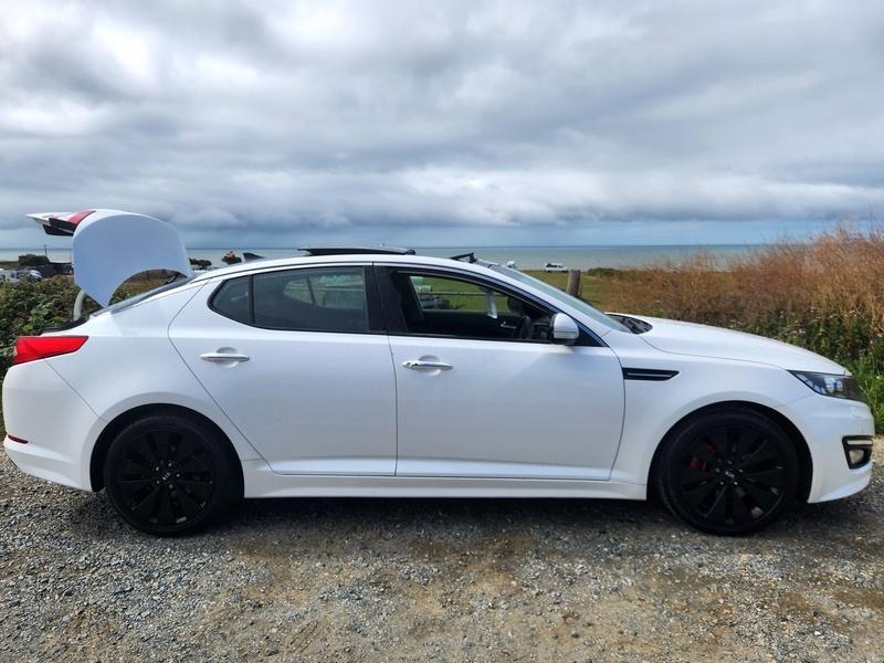 A white Kia Optima viewed from the driver side