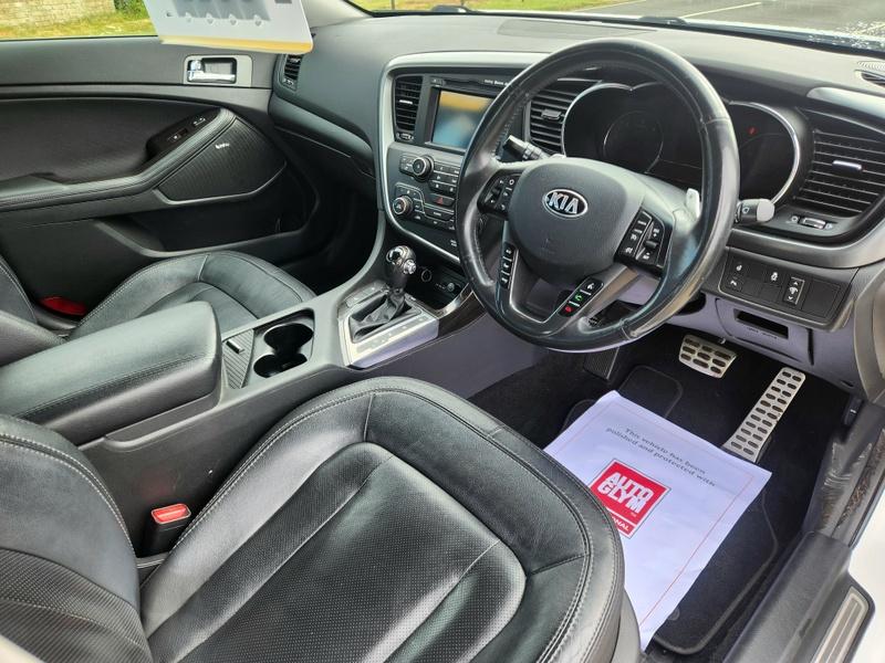 The steering controls of a white Kia Optima viewed from above the driver seat