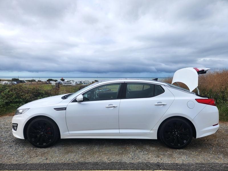 A white Kia Optima viewed from the passenger side
