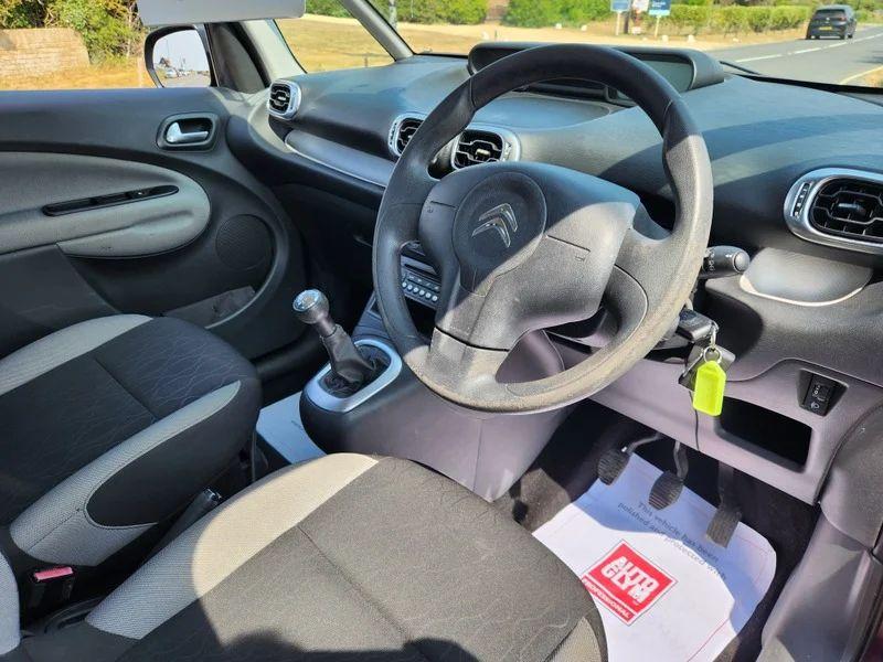 The steering controls of a violet Citroen C3 Picasso viewed from above the driver seat