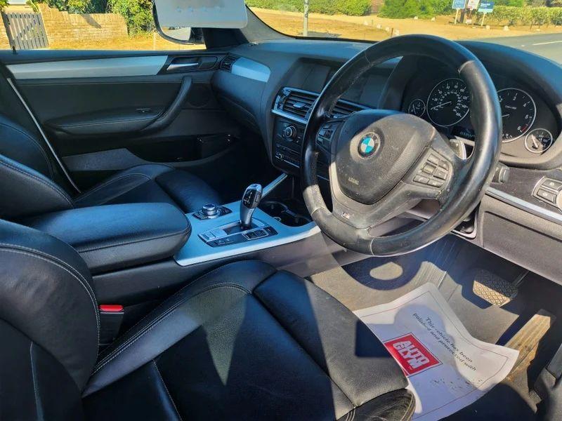 The steering controls of a white BMW X3 viewed from above the driver seat