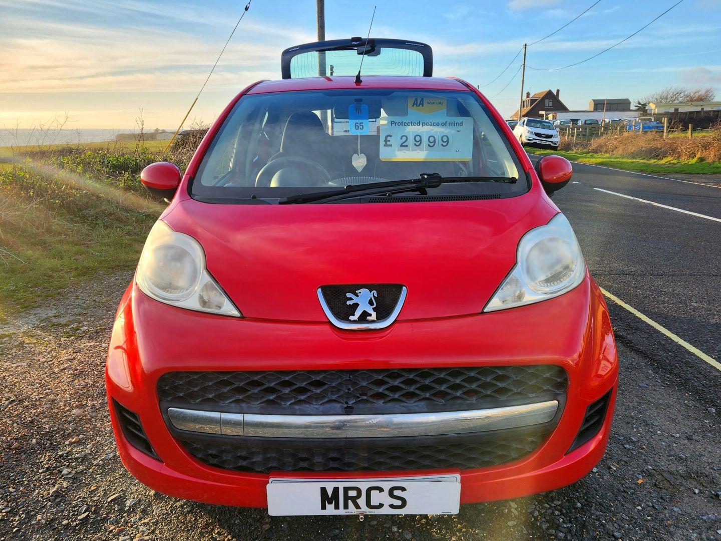 A red Peugeot 107 viewed from the front