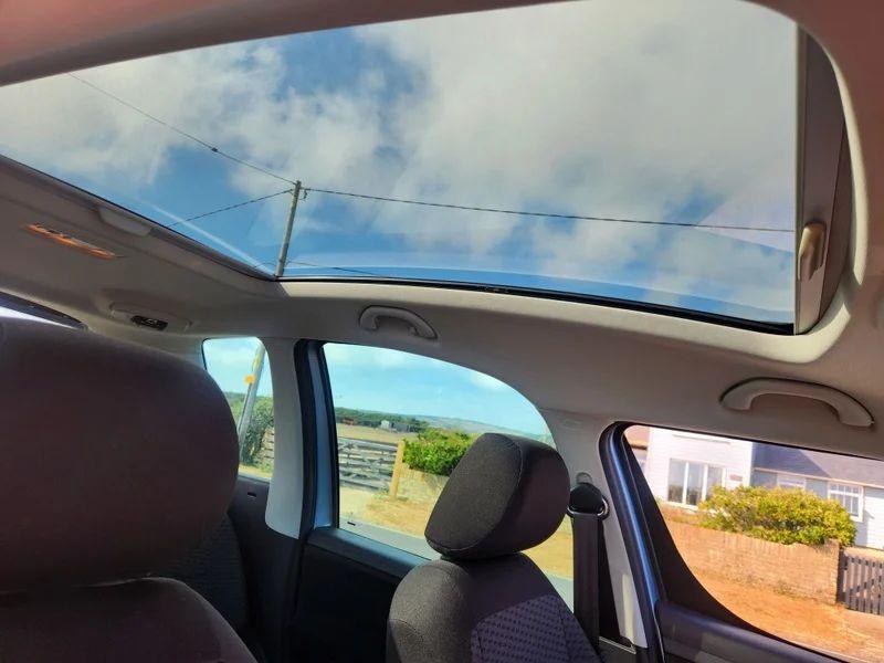 The sunroof of a silver-blue Skoda Roomster viewed up from the driver seat