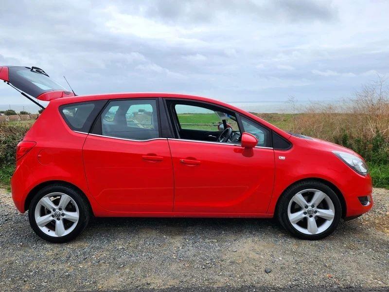 A Magma Red Solid Vauxhall Meriva viewed from the driver side