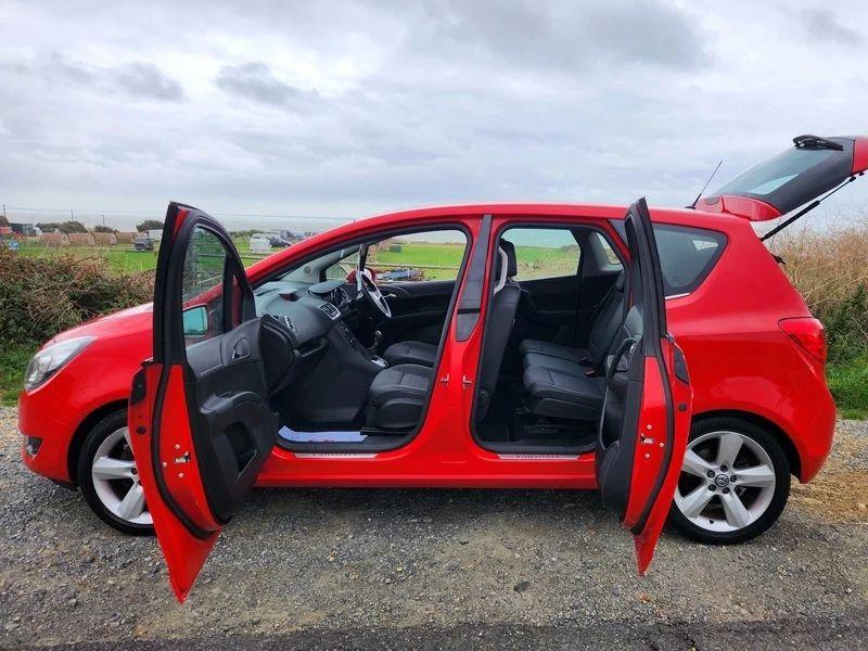 A Magma Red Solid Vauxhall Meriva viewed from the passenger side