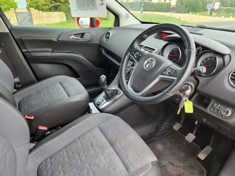 The steering controls of a Magma Red Solid Vauxhall Meriva viewed from above the driver seat