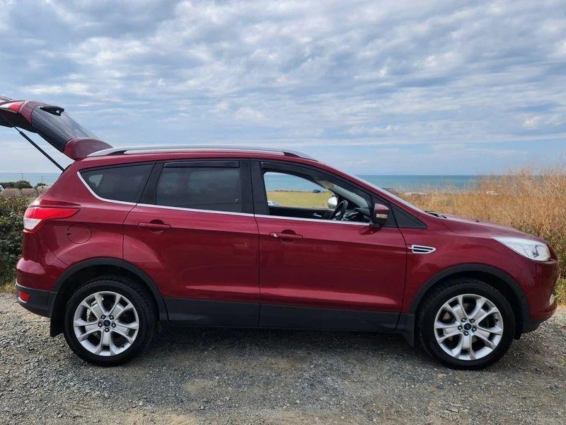A red Ford Kuga viewed from the driver side