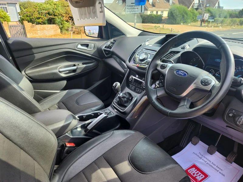 The steering controls of a red Ford Kuga viewed from above the driver seat