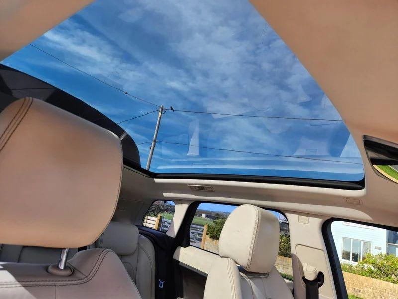 The sunroof of a Santorini Black Range Rover viewed up from the driver seat