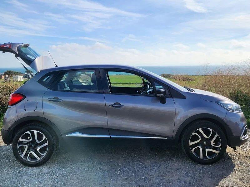 A grey Renault Captur with an open boot viewed from the driver side