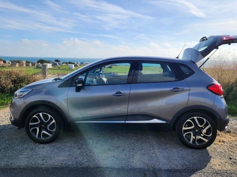 A grey Renault Captur with an open boot viewed from the passenger side