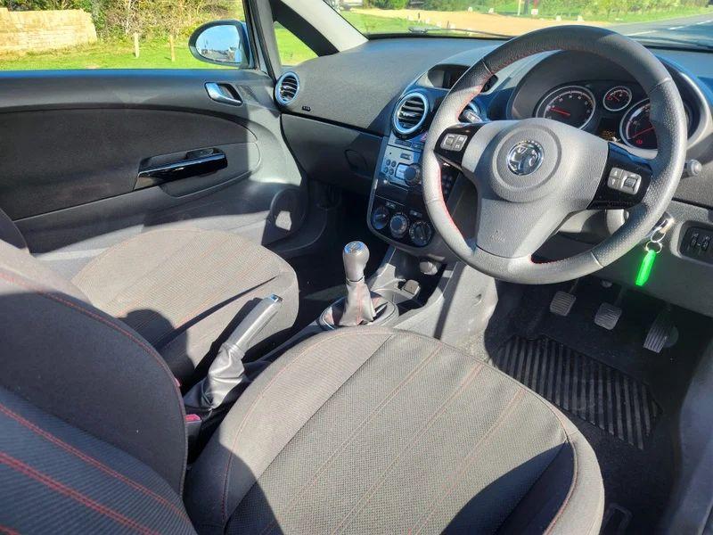 The steering controls of a Snow White Vauxhall Corsa viewed from above the driver seat