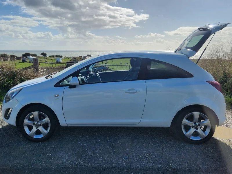 A Snow White Vauxhall Corsa with an open boot viewed from the passenger side