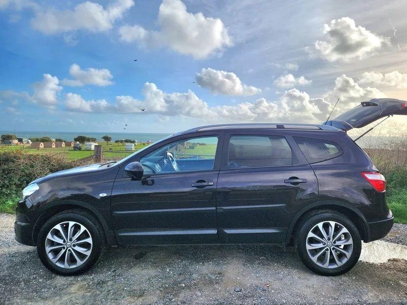 A Nightshade Black Metallic Nissan Qashqai with an open boot viewed from the passenger side